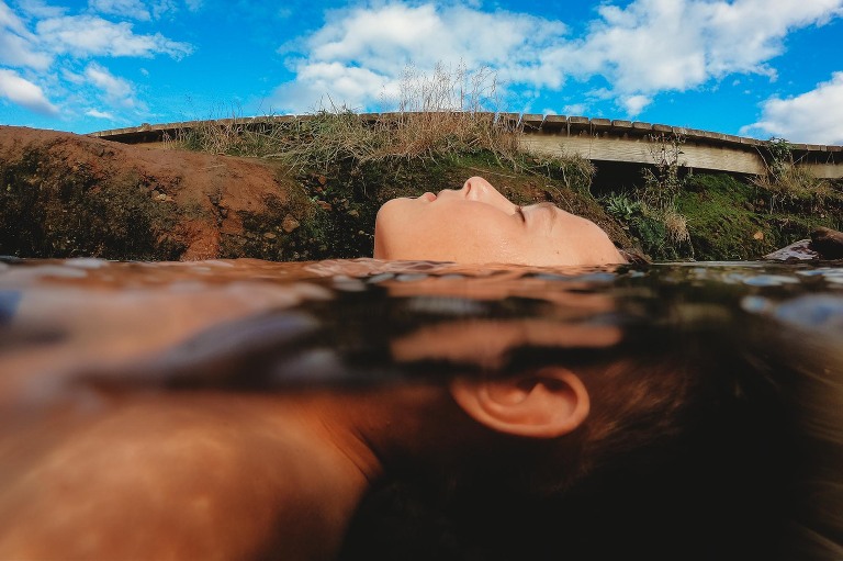 Boy relaxing half submerged in thermal hot river Iceland 