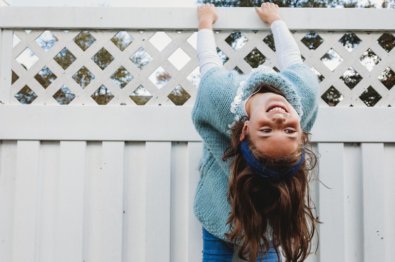 girl hanging on fence