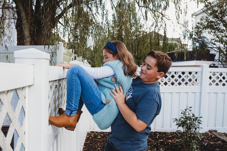 brother helping sister climb fence