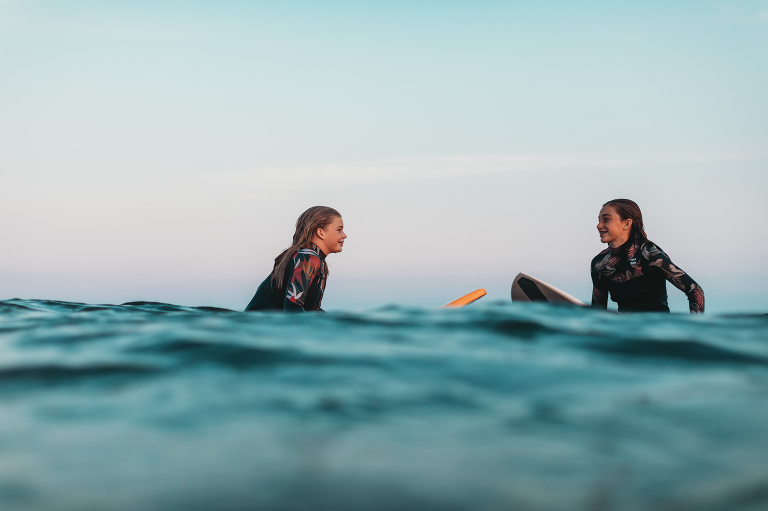 sunset surf session sisters in the water