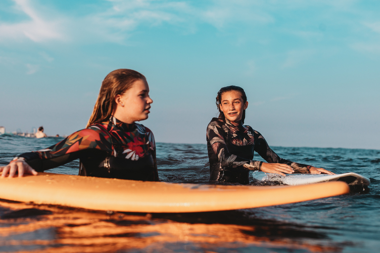 sisters in the water surfing in ocean city during a photo session