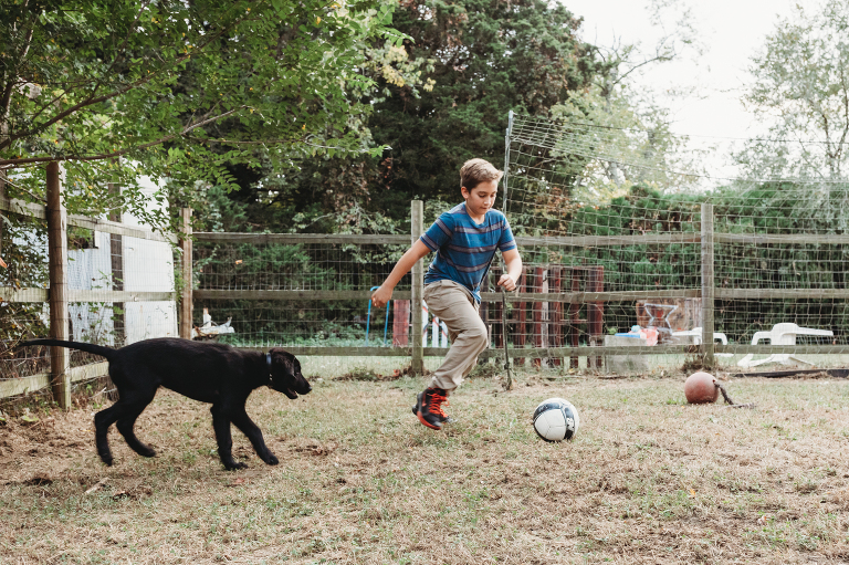 boy playing soccer with puppy