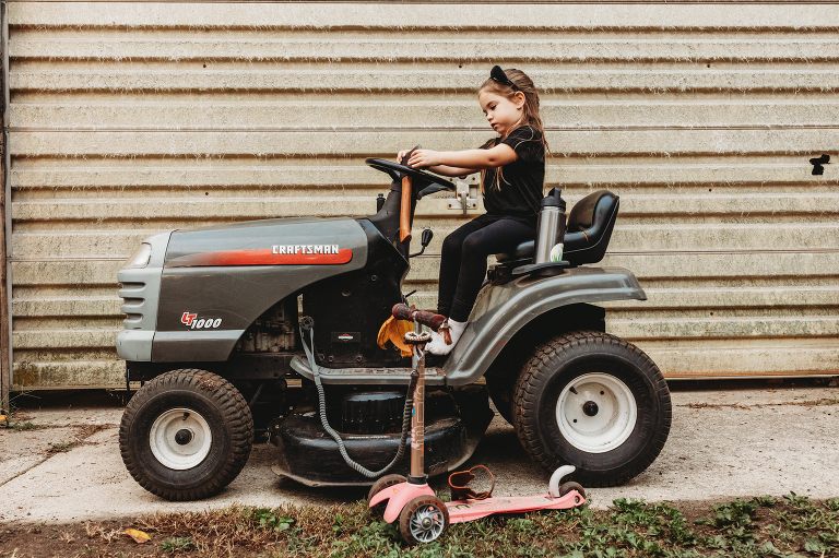 girl playing outside and sitting on tractor