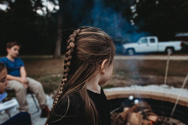 little girl with braid looks at marshmallows being roasted